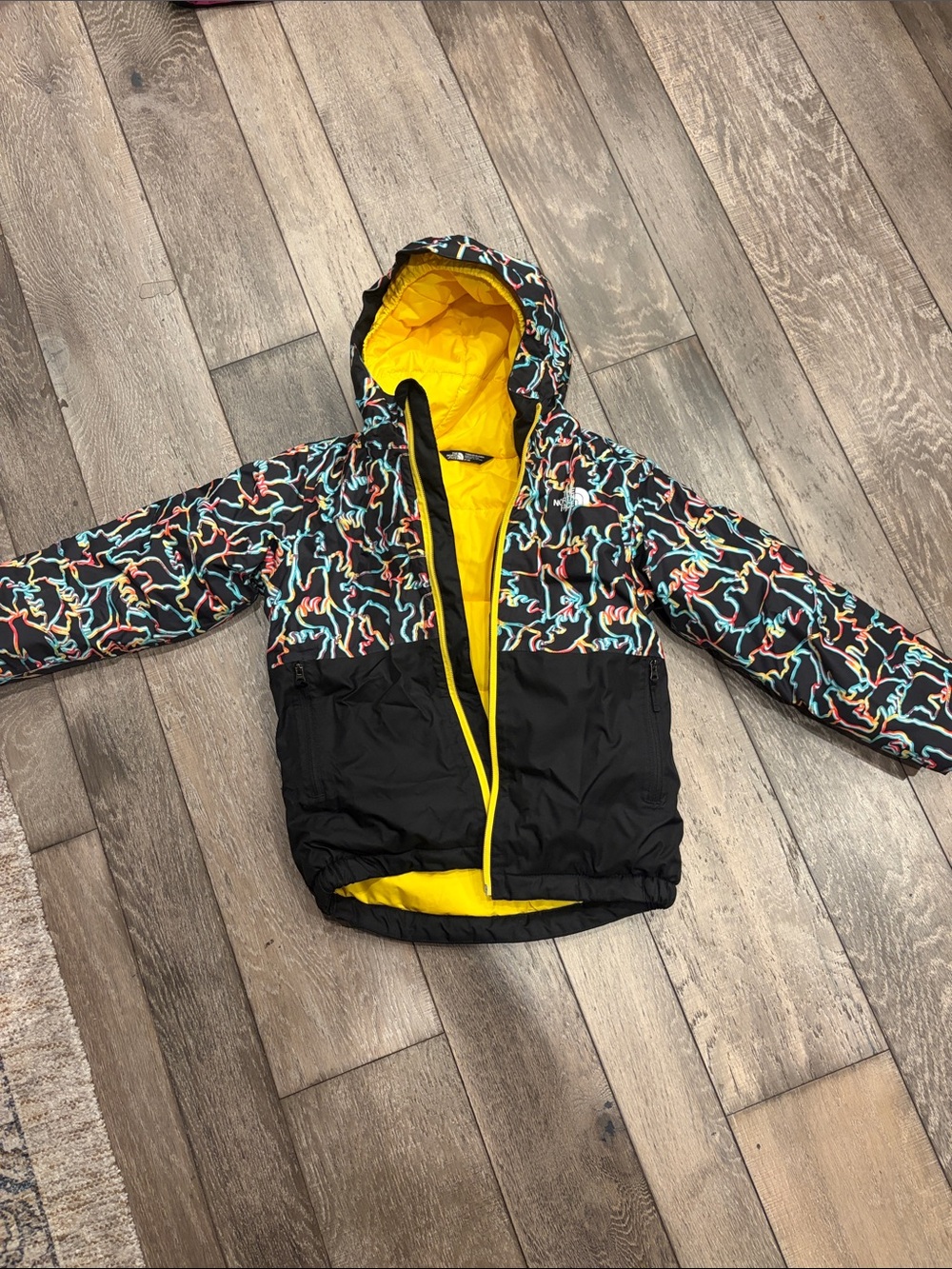 The North Face Kids Black Jacket with Yellow Lining and Multicolor Pattern